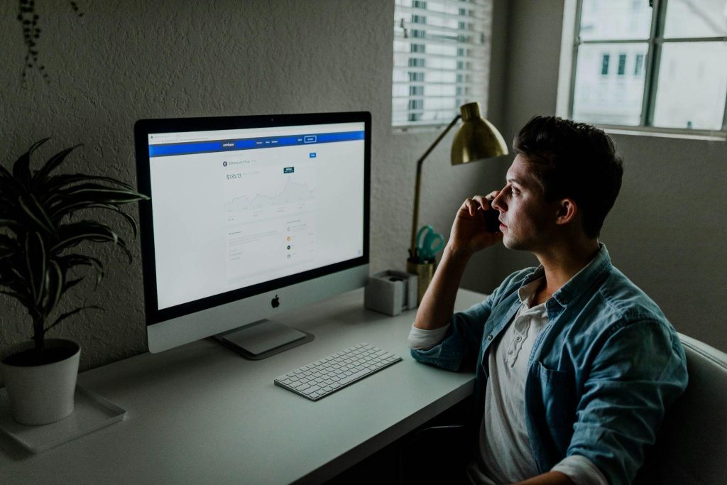 Person sitting at a desk, working on a computer displaying financial charts and graphs.